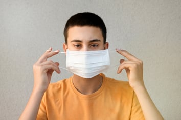 teenage-boy-holding-up-a-face-mask-GL762YQ